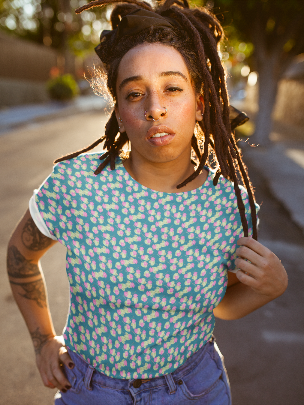Sun kissed dreadlock sister wearing a blue shirt with pink flowers